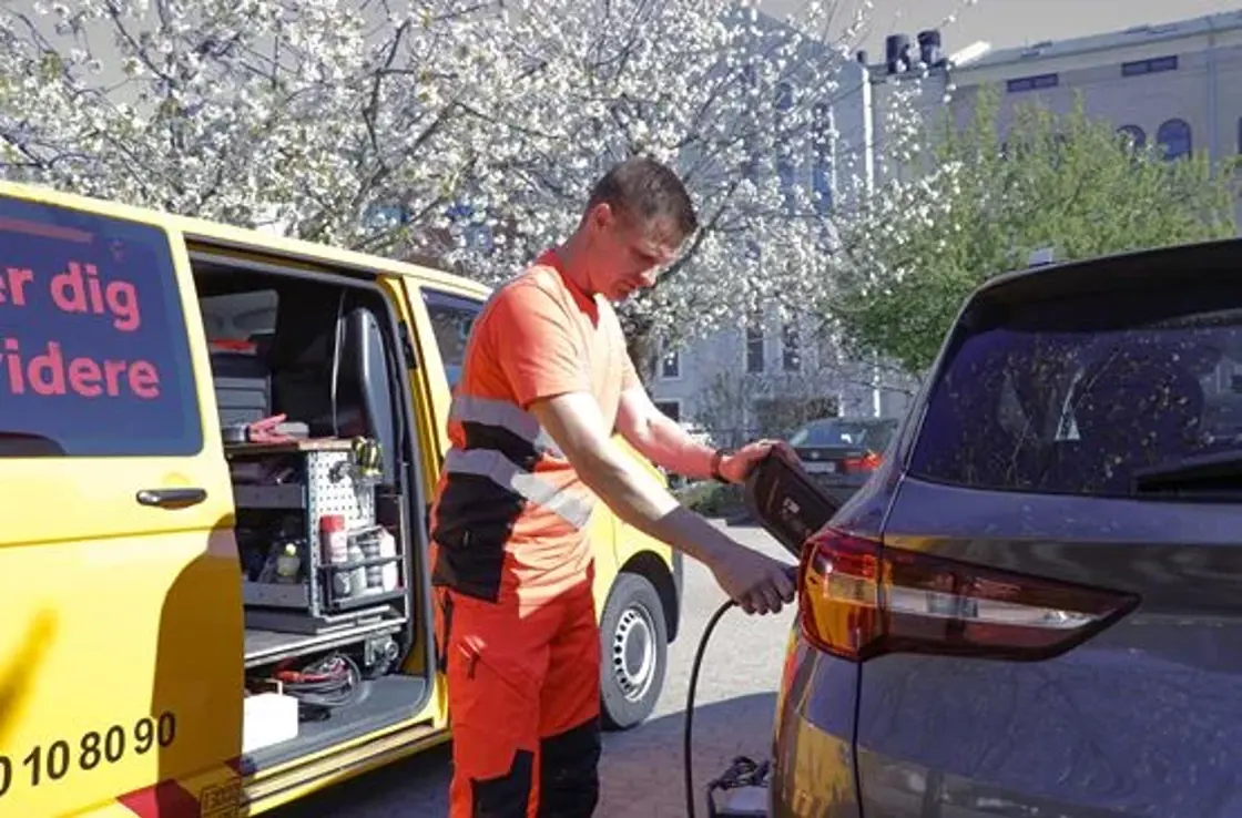 Autoredder står med elkabel og sætter det i bil